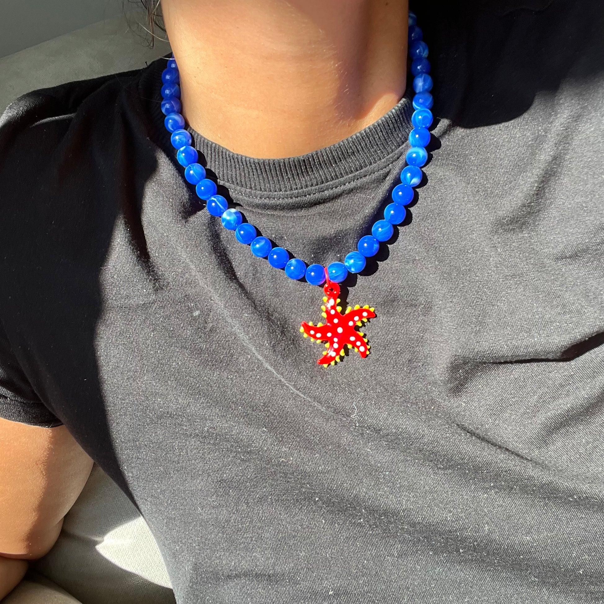 Collar Estrella, con un Dije de Vidrio en forma de Estrella Roja y Perlas Azules
Ulibkas