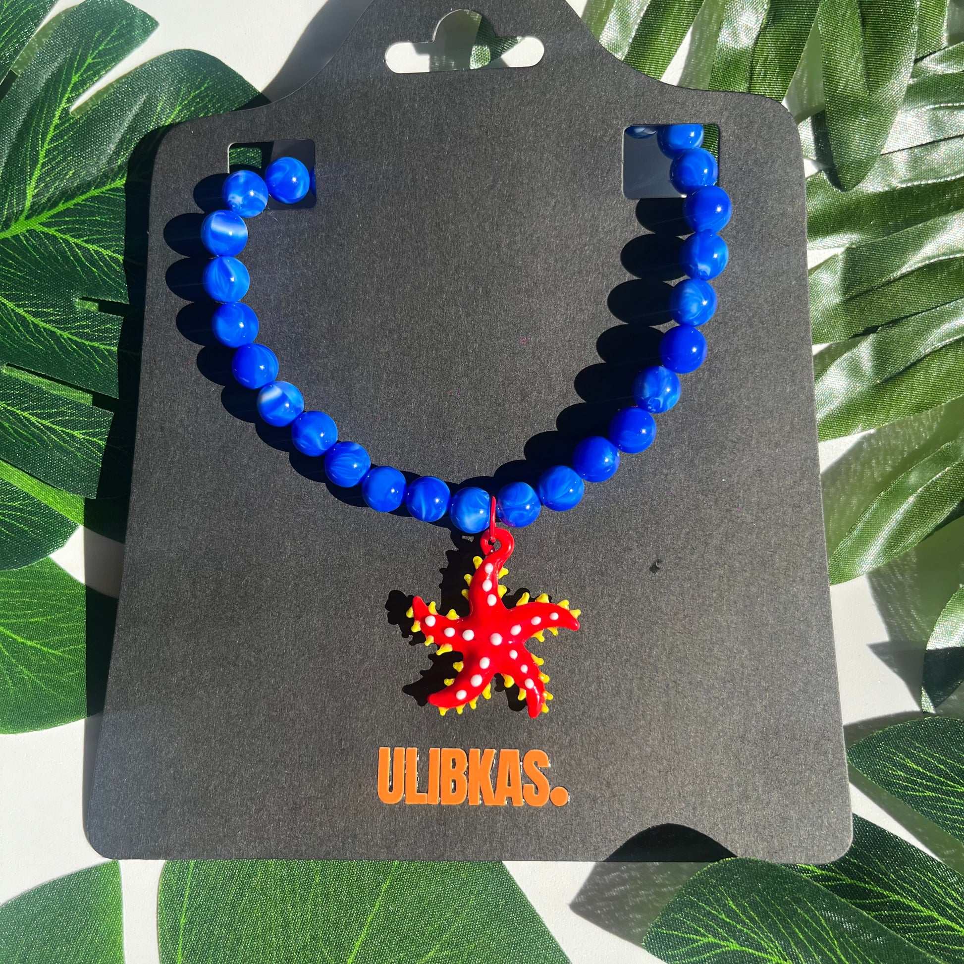 Collar Estrella, con un Dije de Vidrio en forma de Estrella Roja y Perlas Azules
Ulibkas